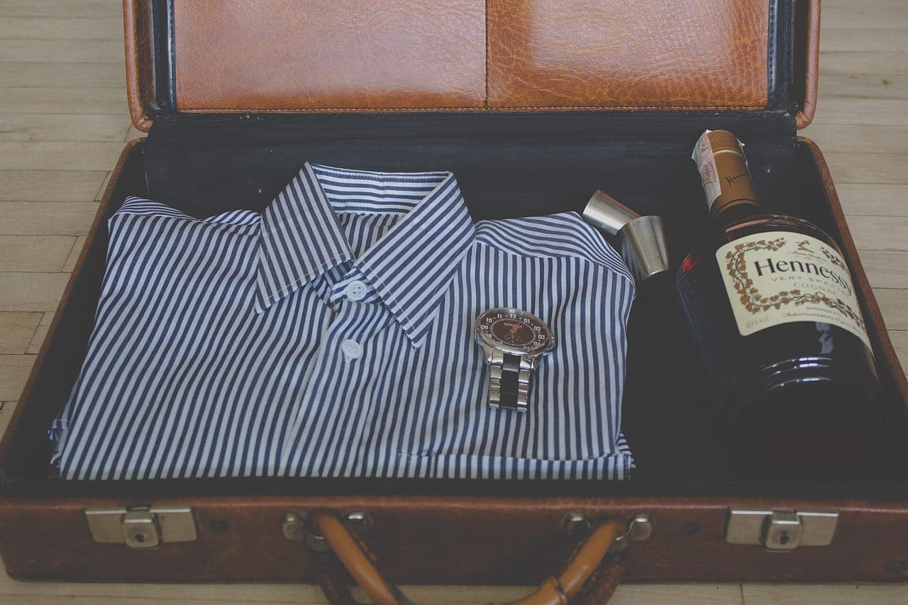 A small set of clothes laid out beside a carry-on bag