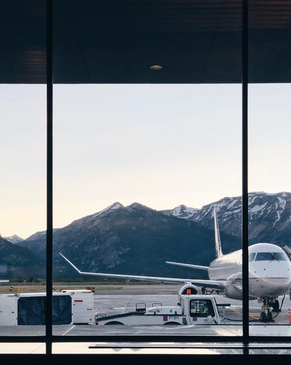 Carry-on luggage beside an airport terminal window